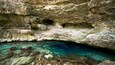 A cave with clear water and rocky formations.