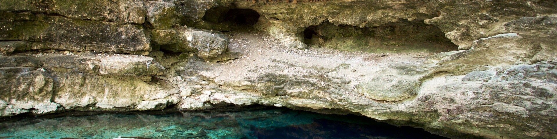 Caverna com água cristalina e formações rochosas.