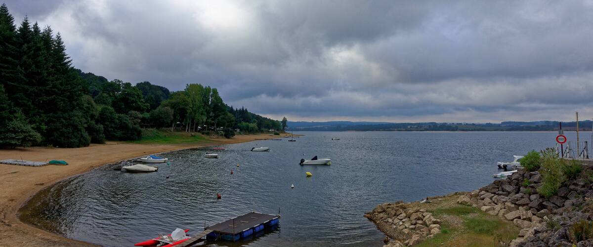 A lake with boats, a sandy beach, and a rocky shoreline.