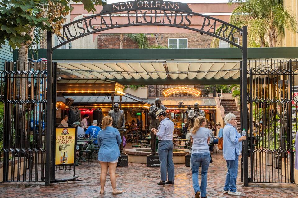 The entrance to New Orleans Musical Legends Park with a brick pathway and a covered area with statues.