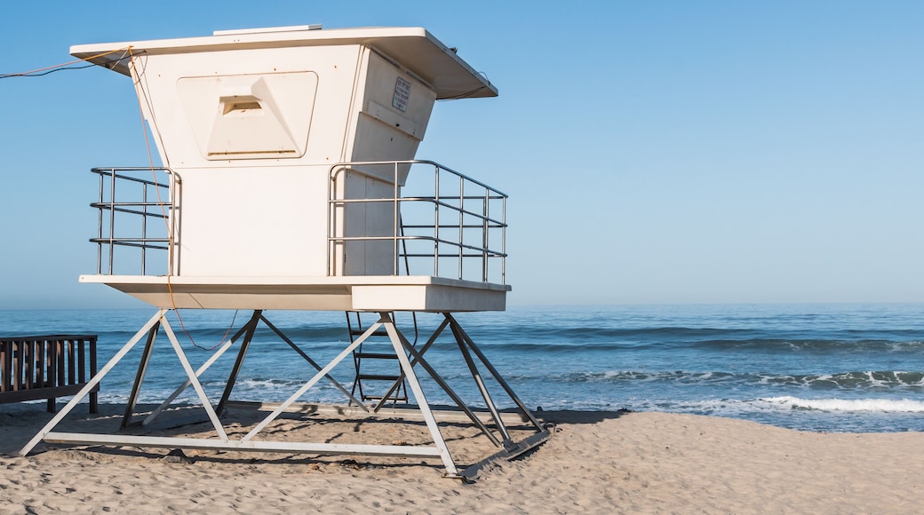 A lifeguard tower on a sandy beach with the ocean in the background.