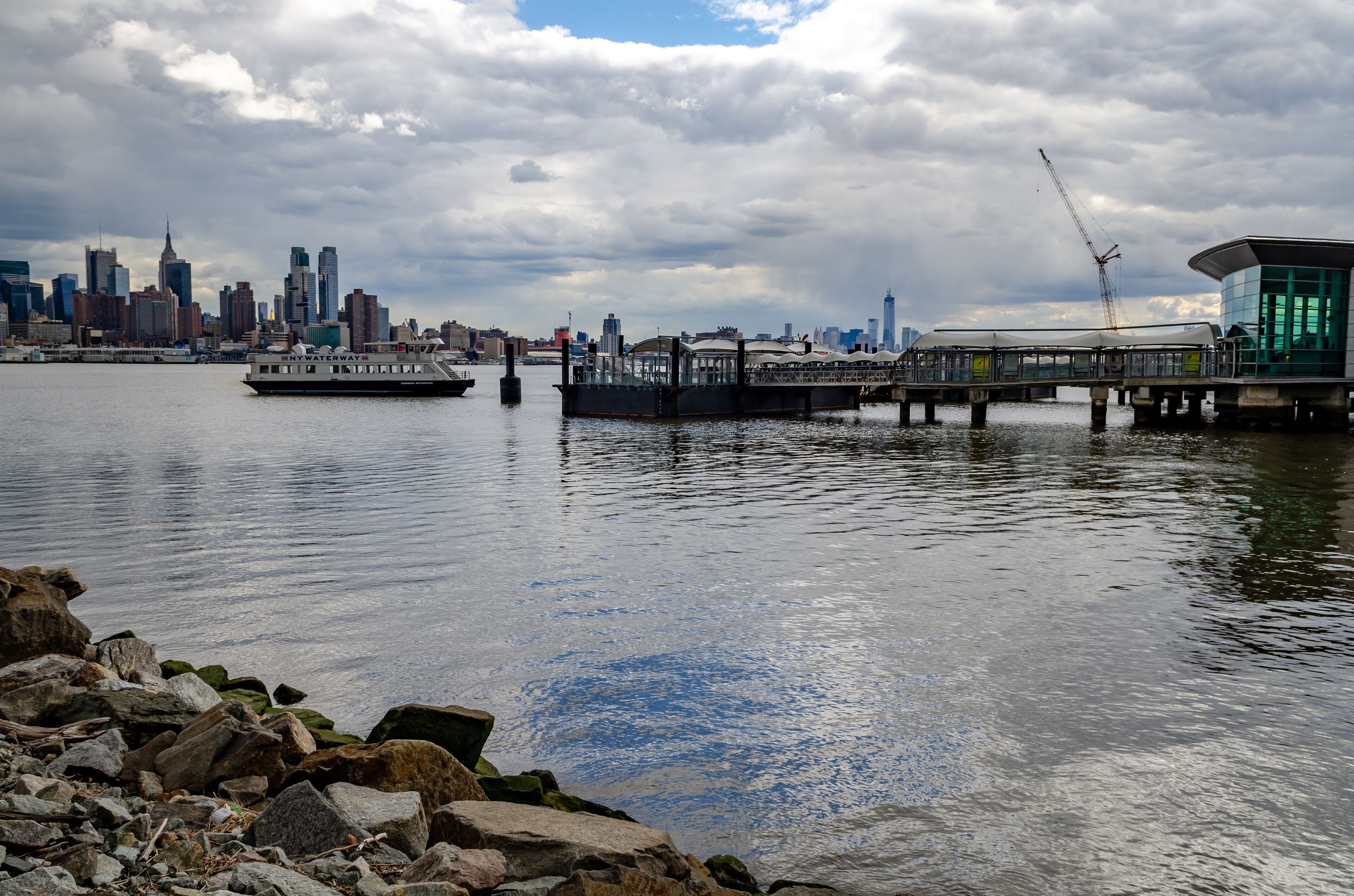 Port Imperial / Weehawken Ferry Terminal at Hudson River, New Jersey with Ferry, side view during cloudy winter day, horizontal