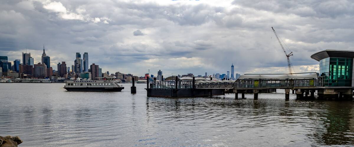 Port Imperial / Weehawken Ferry Terminal at Hudson River, New Jersey with Ferry, side view during cloudy winter day, horizontal