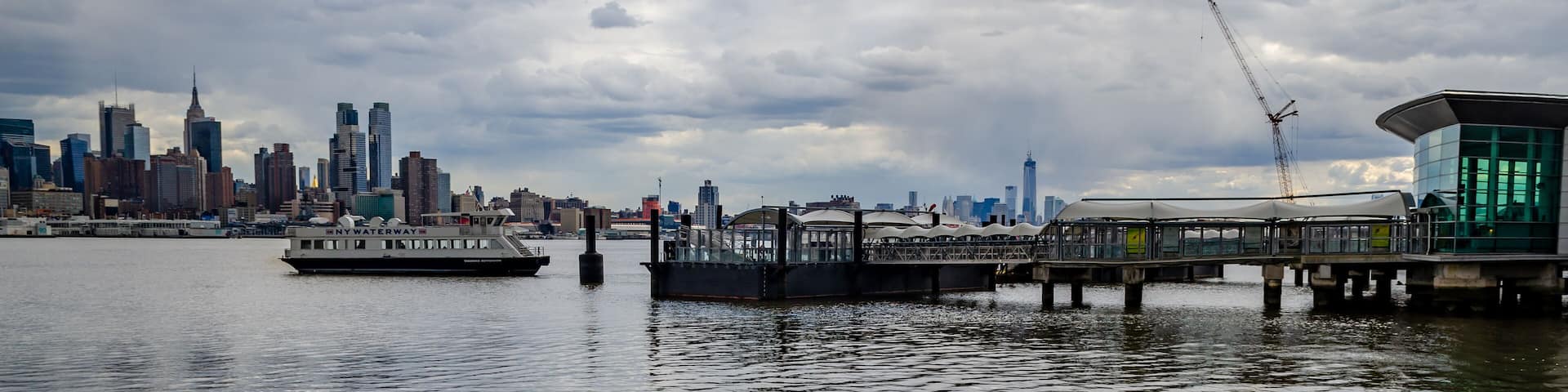 Port Imperial / Weehawken Ferry Terminal at Hudson River, New Jersey with Ferry, side view during cloudy winter day, horizontal