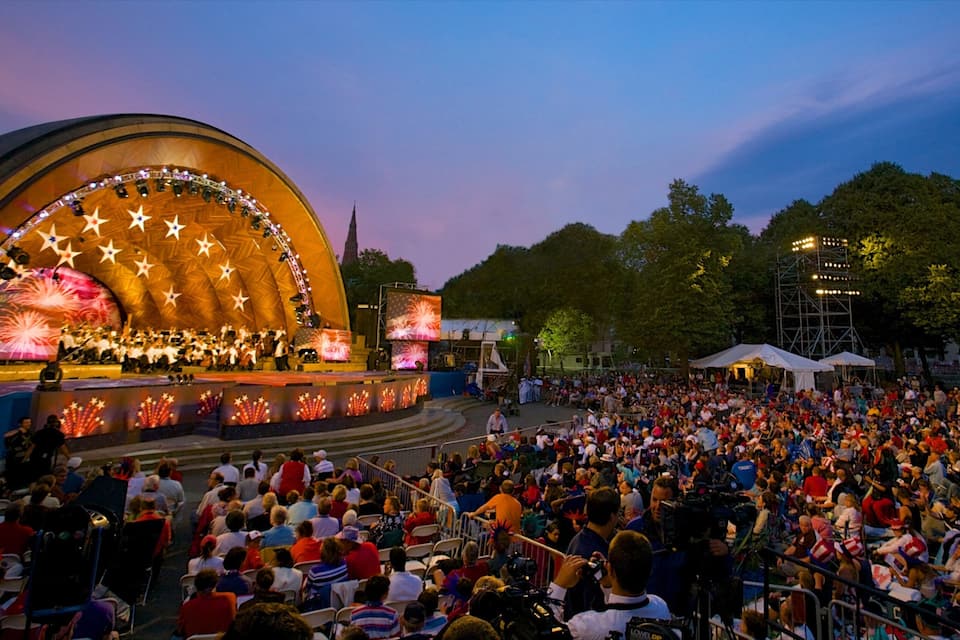A large outdoor concert with a stage decorated with stars and fireworks.
