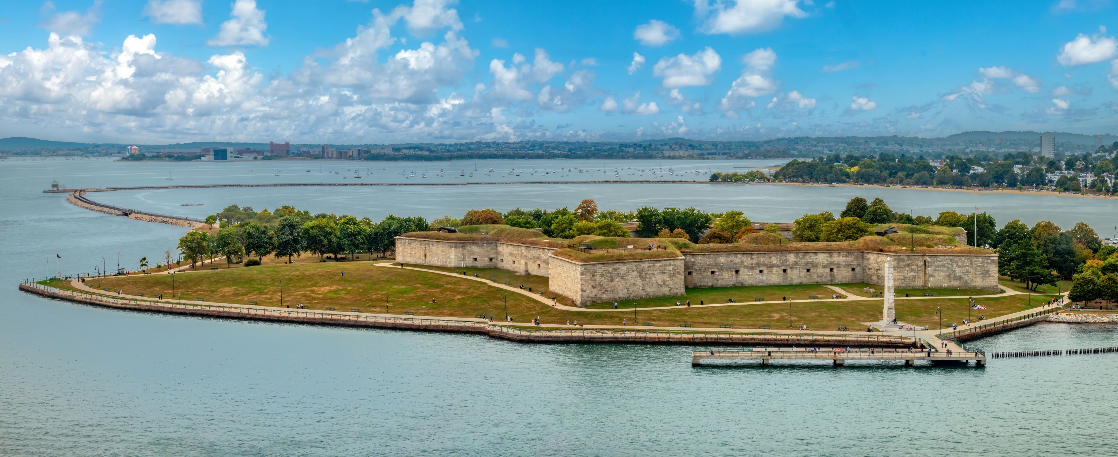 A coastal fortification with a lighthouse, surrounded by water and greenery.