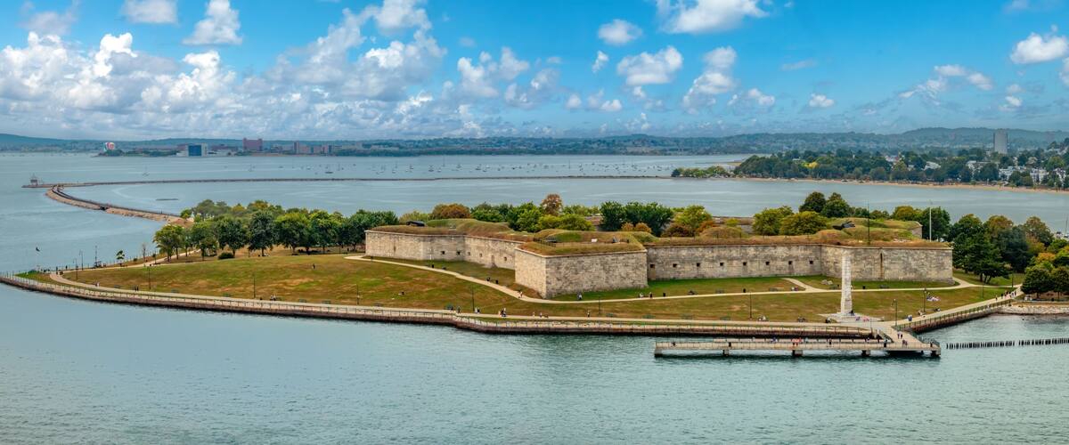 A coastal fortification with a lighthouse, surrounded by water and greenery.
