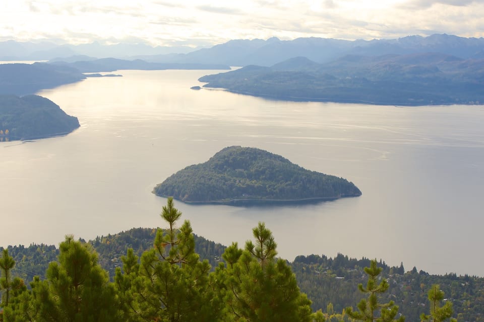 A large lake surrounded by mountains, with a small island in the center.