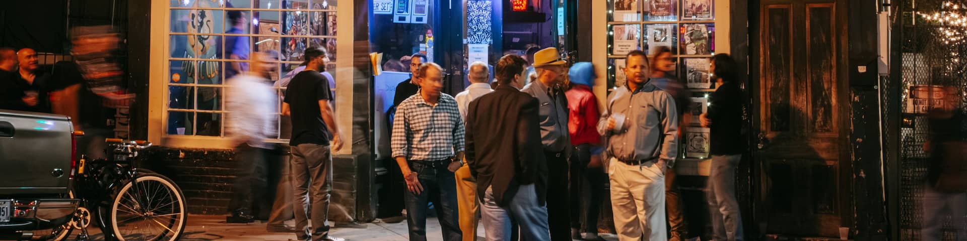 A busy street scene outside a building with large windows and a sign that reads "The Spotted Cat Music Club."