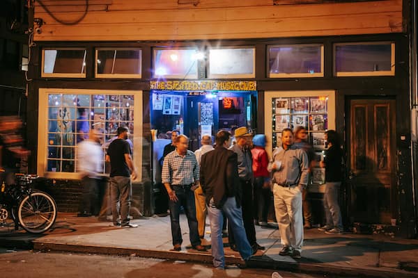 Une rue animée devant un immeuble aux grandes fenêtres, sur lequel on peut lire l’inscription « The Spotted Cat Music Club ».