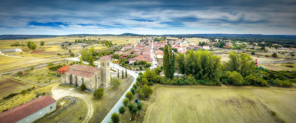 A rural village with a prominent church, surrounded by fields and trees.