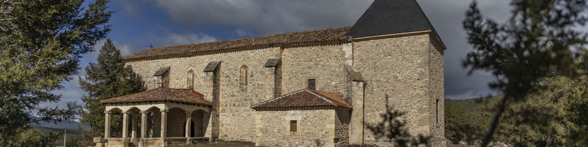 Uma igreja de pedra com uma torre de sino e um pequeno anexo.