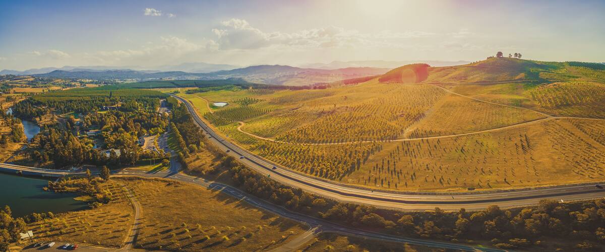 A winding highway through a hilly landscape with a river and forested areas.