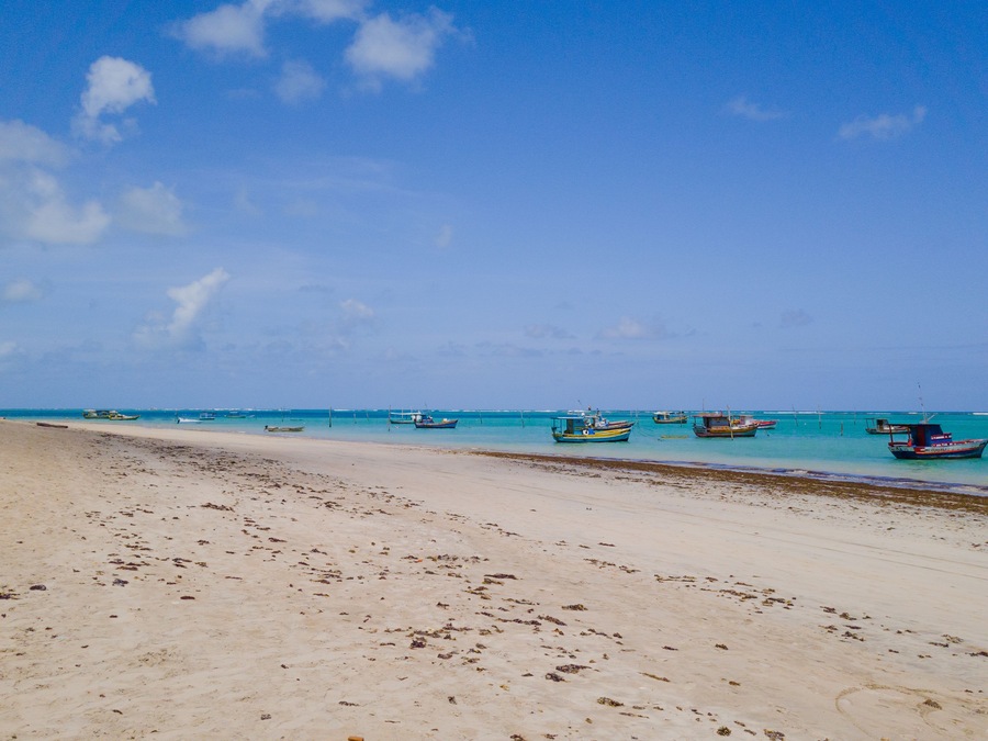 São José da Coroa Grande Beach, Pernambuco, Brazil featuring calm turquoise waters, anchored fishing boats, creating a unique tropical setting.