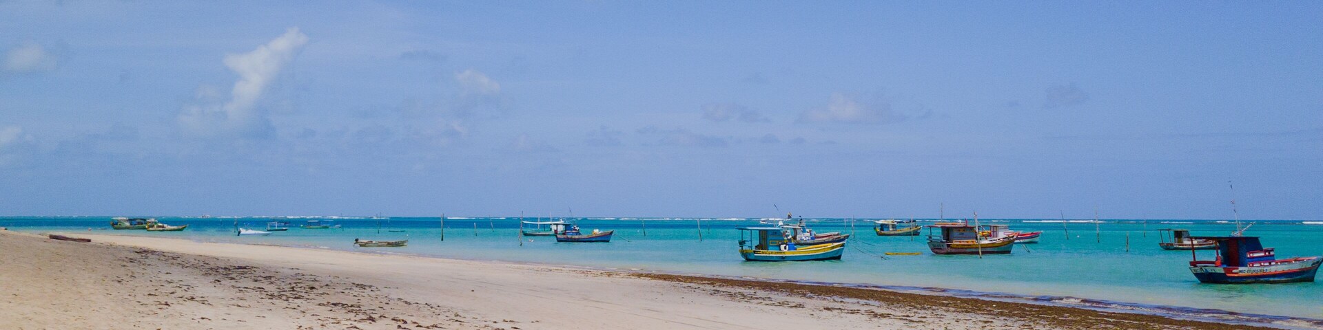 São José da Coroa Grande Beach, Pernambuco, Brazil featuring calm turquoise waters, anchored fishing boats, creating a unique tropical setting.