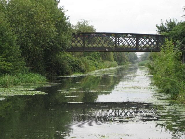 Grand Union Canal (Slough Arm): Trout Lane bridge Trout Lane pre-dated the 1882-built canal as an old track and it must have been incumbent on the canal's builders to sustain the right of way across their new watercourse. This presumably is the original girder and latticework bridge mounted on brick abutments on either side. Today it is only in use as a footpath crossing of the canal. This view was taken looking eastwards from the aqueduct constriction.