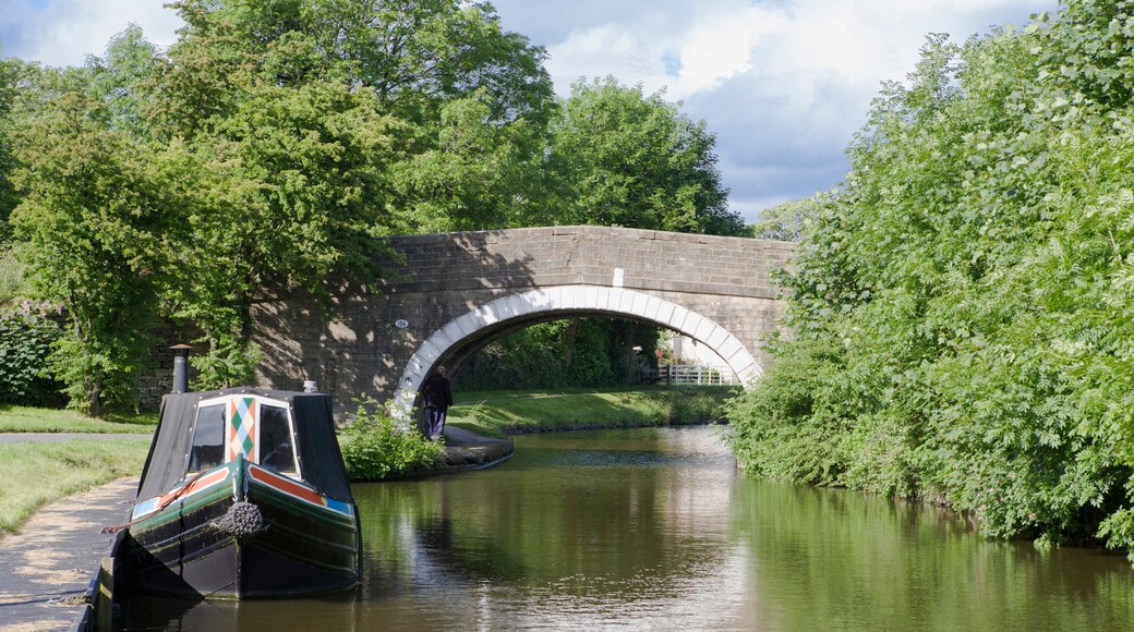 A quiet stretch of the Leeds and Liverpool Canal near Barnoldswick, with a single narrowboat moored alongside the tow-path, and an old canal bridge in the middle distance.
