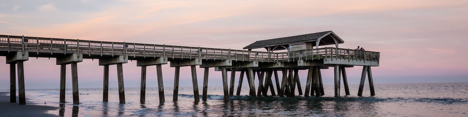 Wide angle view of the Tybee Island Pier in Georgia. Colorful sunset with pinks and purple colors in the sky