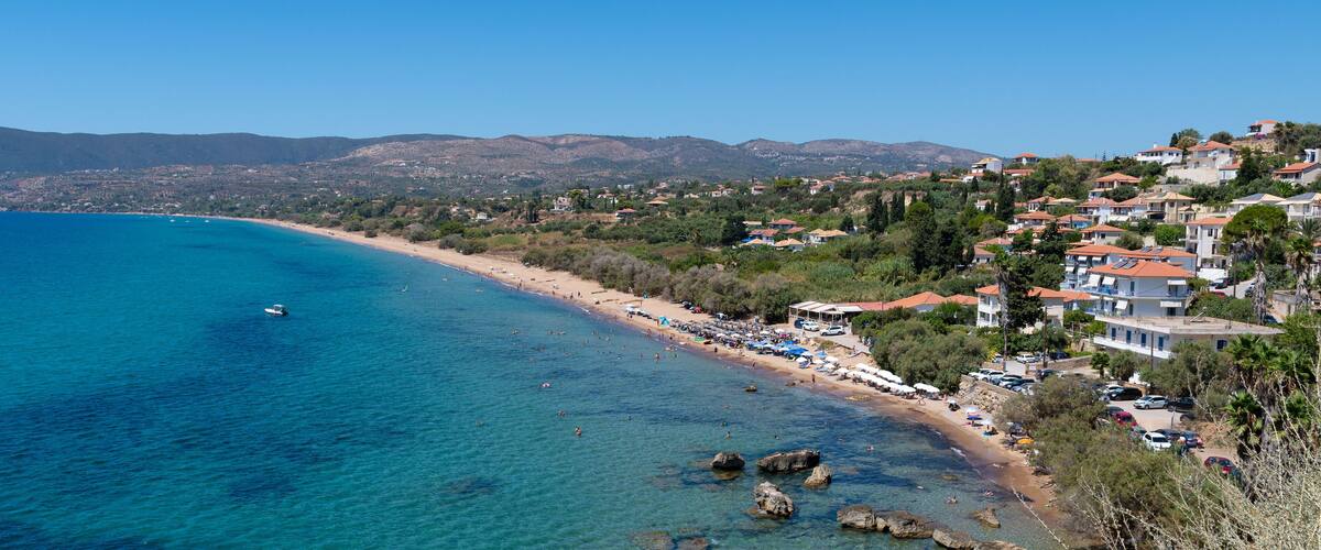A coastal town with clear blue waters, rocky shoreline, and hillside buildings.