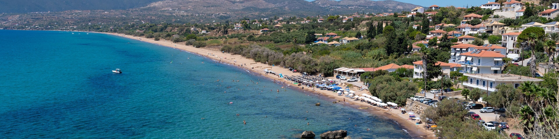 A coastal town with clear blue waters, rocky shoreline, and hillside buildings.