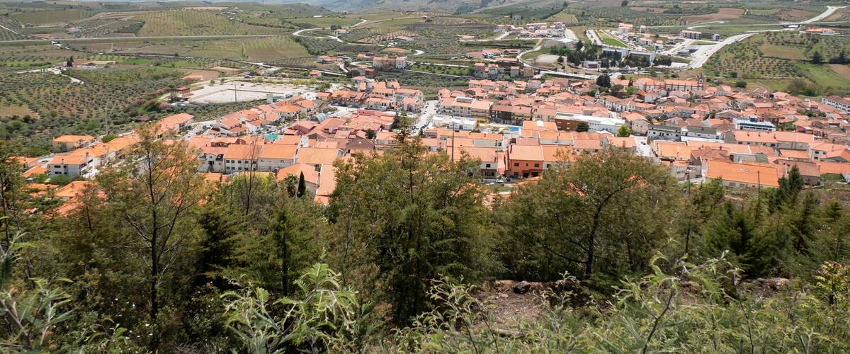 A town with orange-roofed buildings nestled in a valley surrounded by hills.