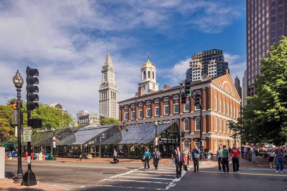 A city intersection with historic buildings, a clock tower, and a modern skyscraper.