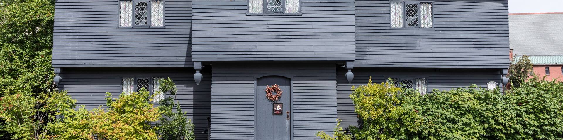 Une maison à deux étages, à l’extérieur d’un bleu foncé, avec un porche à l’avant et une guirlande décorative sur la porte.
