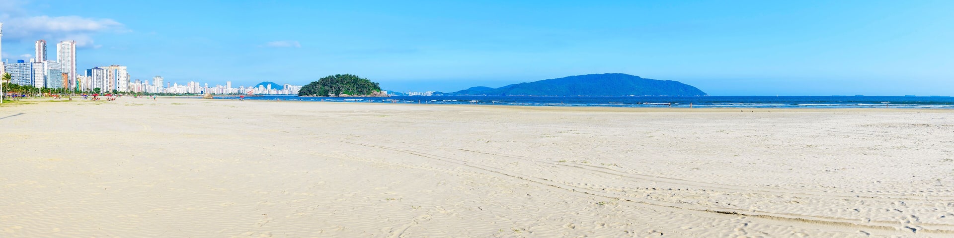 Panoramic view of a brazilian Paulista beach with a huge band of waterfront sand on beautiful day. Photo at Itarare beach, Sao Vicente city with the view to Jose Menino beach, at Santos SP city.