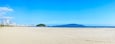 Panoramic view of a brazilian Paulista beach with a huge band of waterfront sand on beautiful day. Photo at Itarare beach, Sao Vicente city with the view to Jose Menino beach, at Santos SP city.
