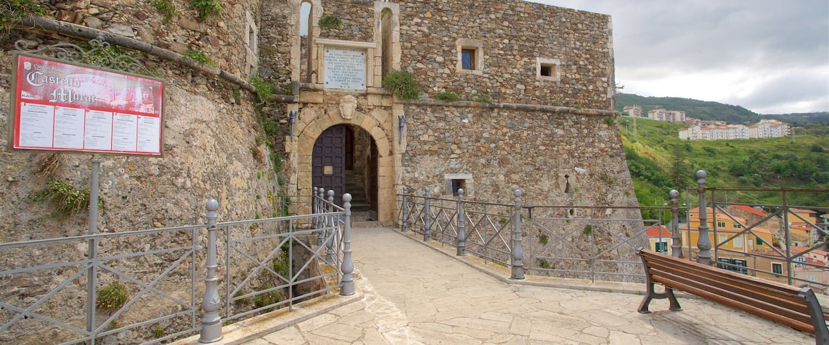 A stone fortress with a signboard, a metal railing, and a bench.
