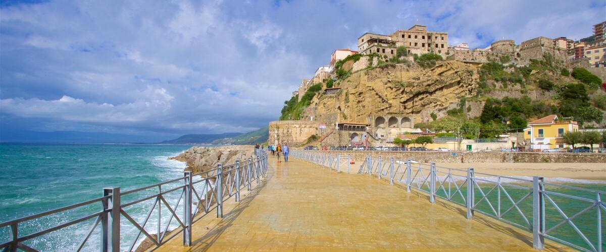 A coastal walkway with a historic building on a cliff, overlooking the sea.