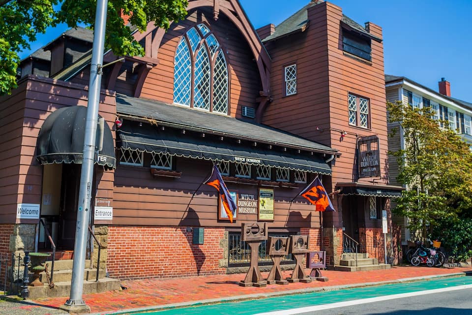 A red brick building with a large arched window and a sign reading "Witch Dungeon Museum".