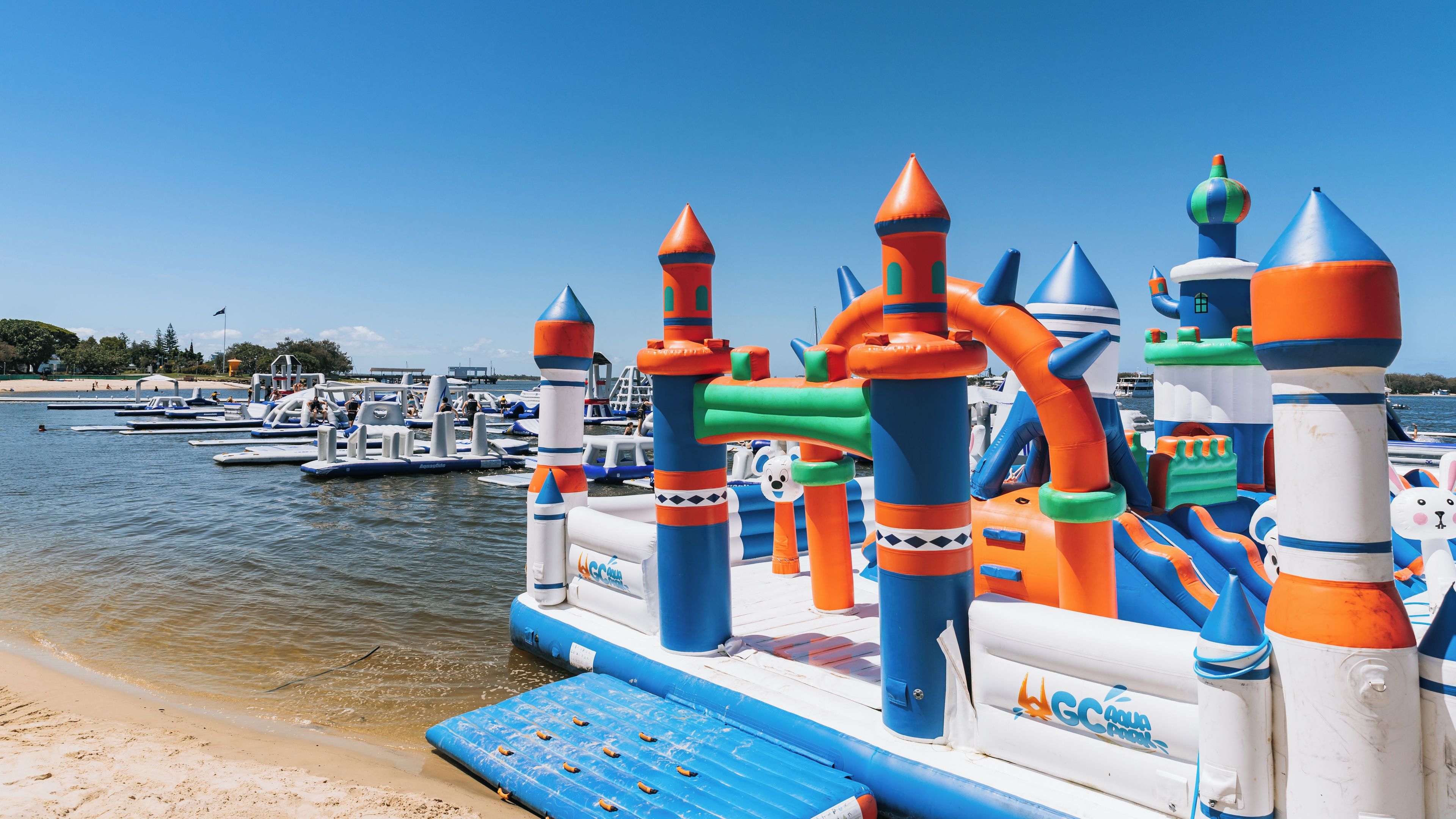 A colorful inflatable play structure by the water.