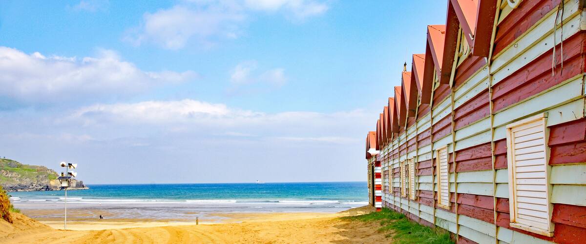 A sandy beach with a wooden building and a lifeguard tower.