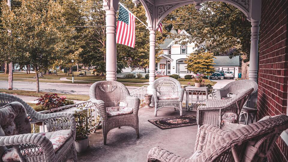 A porch with wicker furniture and American flags.