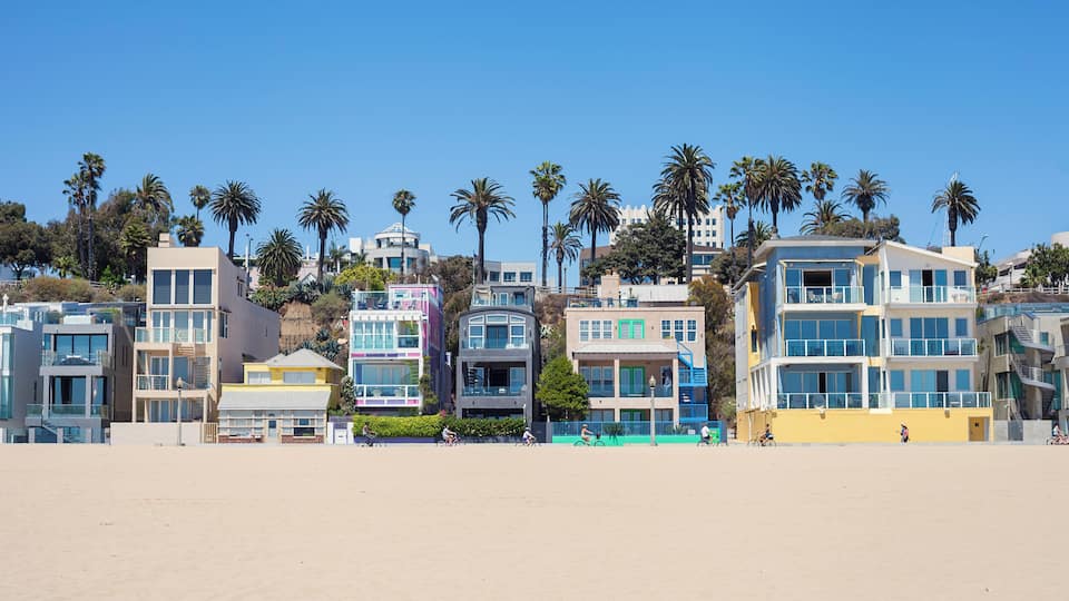 A beach with colorful buildings and palm trees.