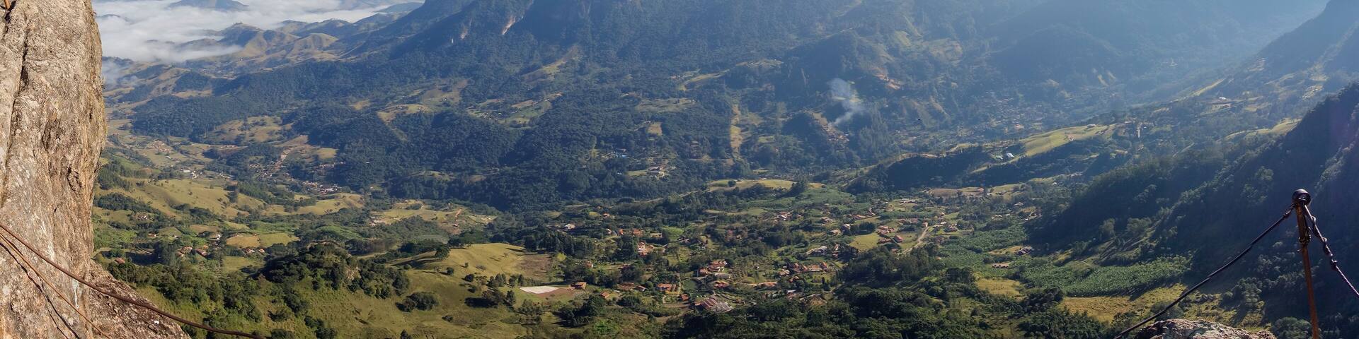 A mountainous landscape with a clear sky, a rocky outcrop on the left, and a village in the valley below.