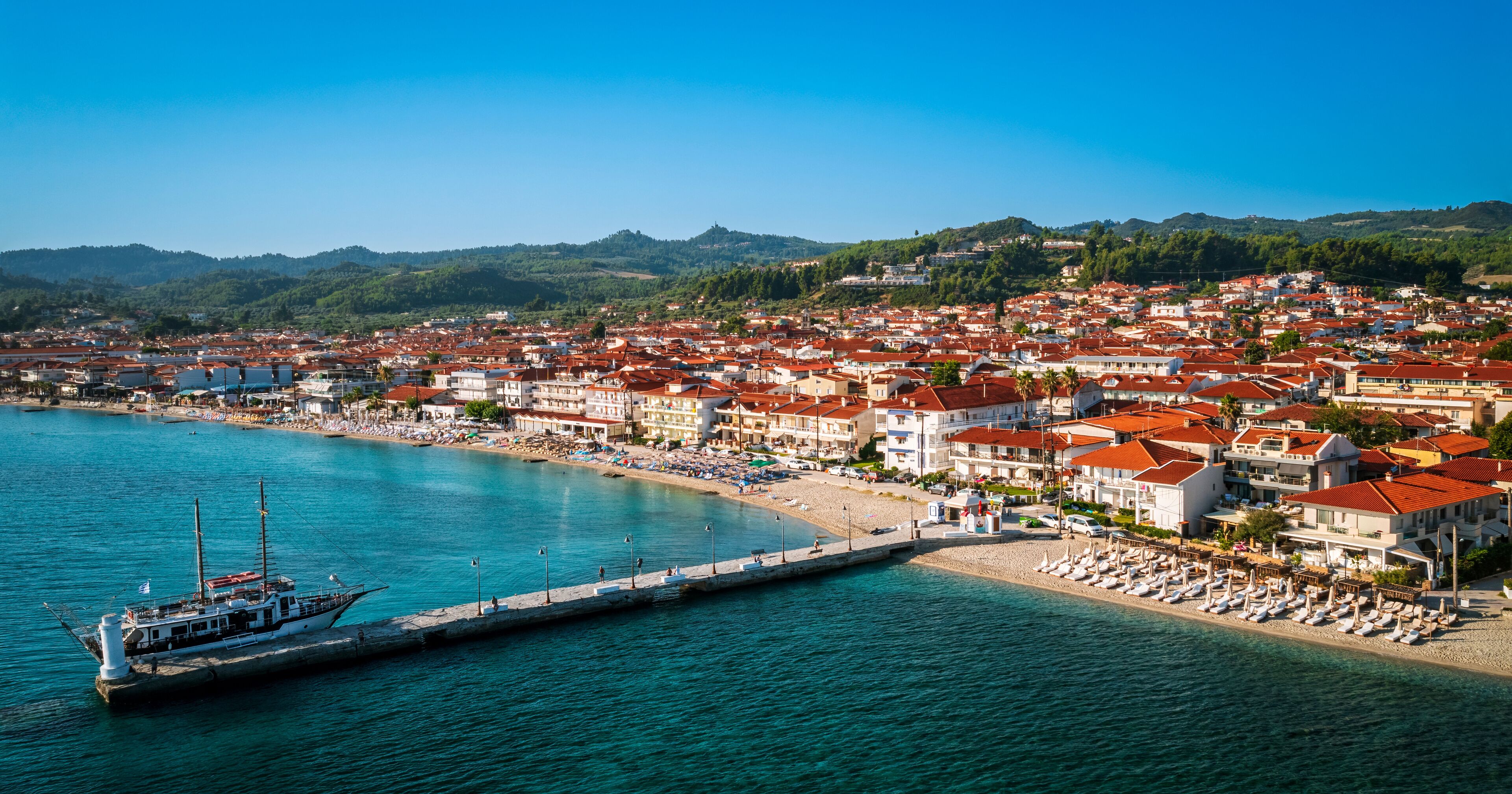 A coastal town with a marina, beach, and red-roofed buildings.