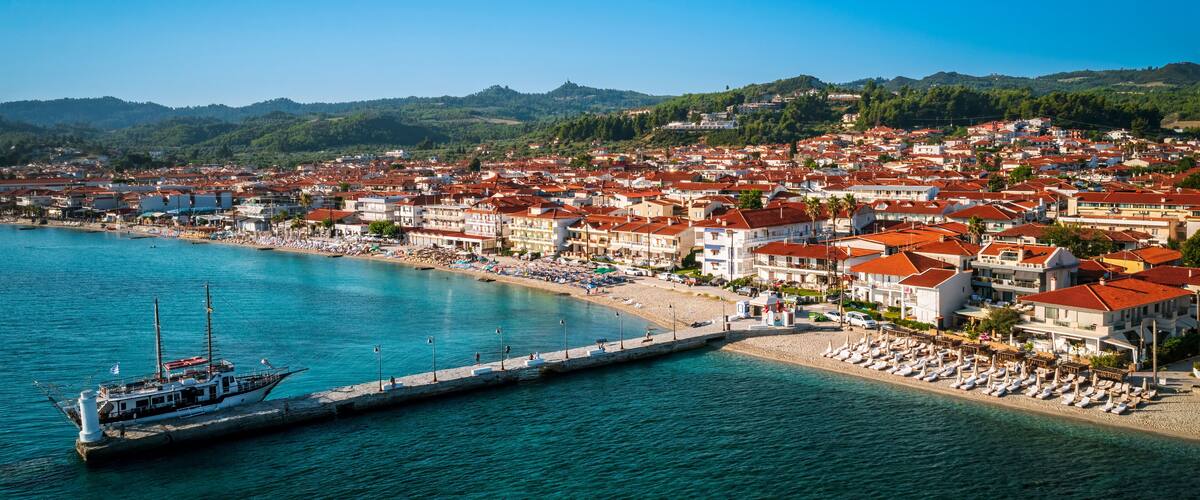 A coastal town with a marina, beach, and red-roofed buildings.