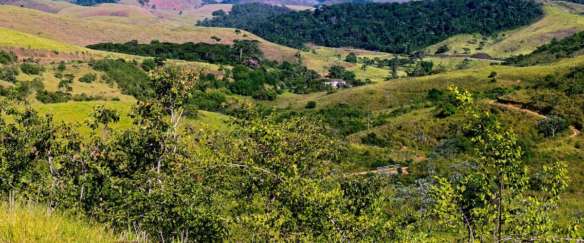 Rolling hills, a small white building, and distant mountains under a clear sky.
