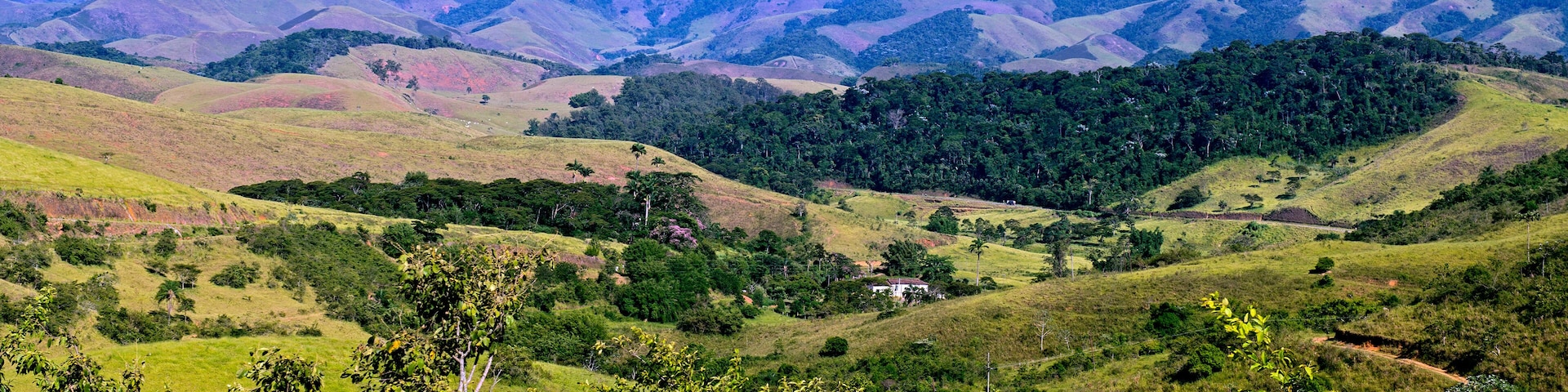 Rolling hills, a small white building, and distant mountains under a clear sky.