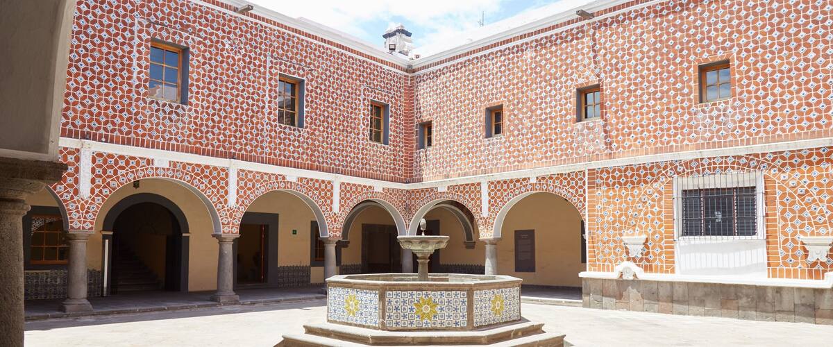 A courtyard with patterned walls, arches, and a central fountain.