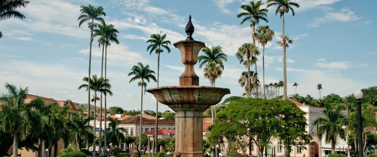 A fountain surrounded by palm trees and buildings.