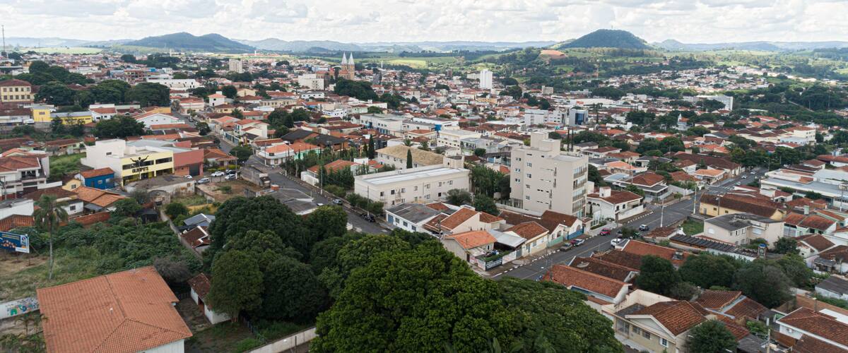A panoramic view of a city with dense housing, a prominent church tower, and rolling hills in the background.