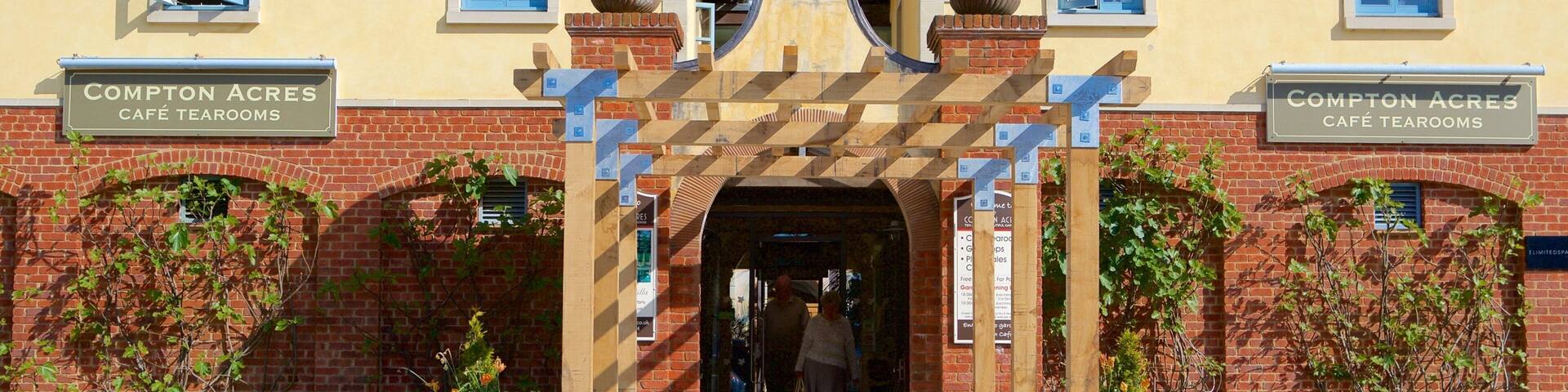 A building with signs reading "Compton Acres Café Tearooms" and a wooden archway entrance.