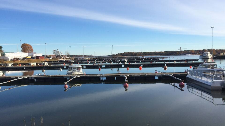 A marina with multiple docks and boats, calm water, and a clear sky.