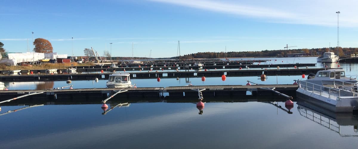 A marina with multiple docks and boats, calm water, and a clear sky.
