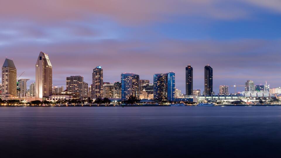 A city skyline with high-rise buildings and a bridge over a body of water.