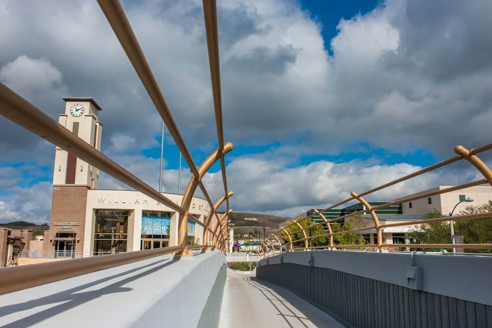 A pedestrian bridge with a clock tower and a building labeled "William A. Brindley Building."