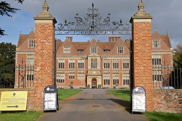 A large, historic building with a prominent entrance gate, brick walls, and a symmetrical facade.